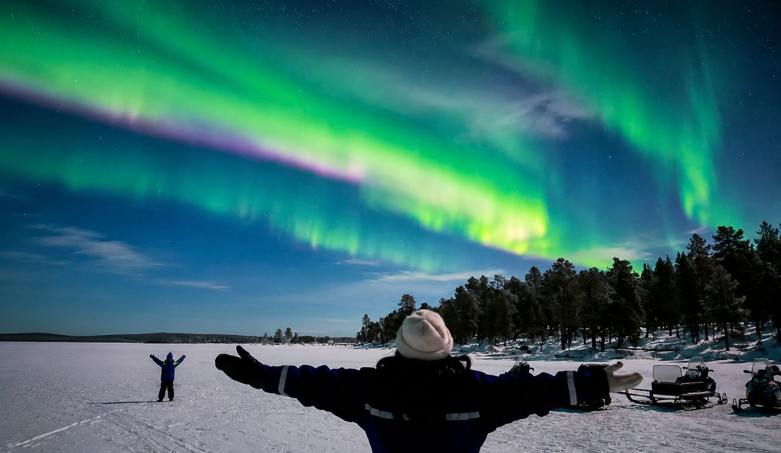 Viaje a Laponia en familia observando auroras boreales sobre un paisaje nevado